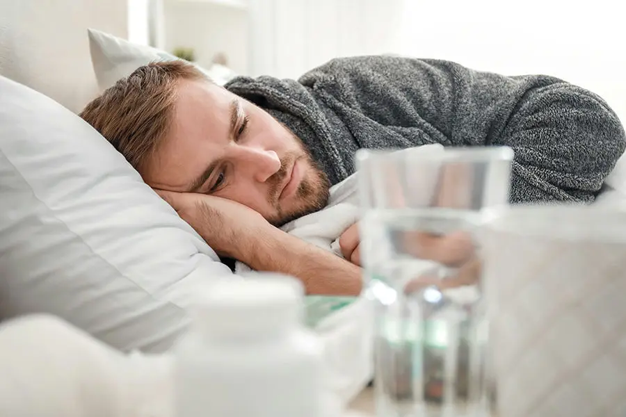 Person rehydrating with water after alcohol use showing dehydration symptoms and stomach cramps.