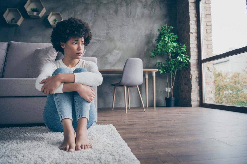 Woman sitting on the floor, reflecting the feeling of the summertime blues