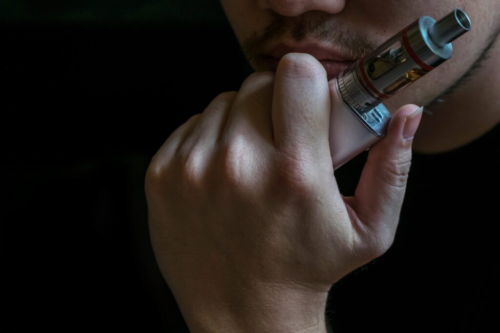 Individual holding a vape, highlighting the hidden risks of vaping, Zyn, and nicotine products